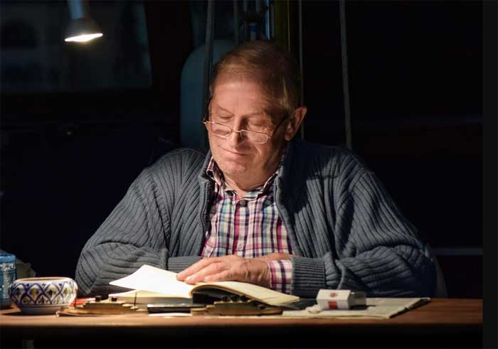 Man with lamp reading a book