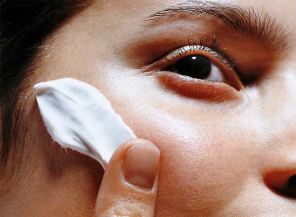 woman applies lotion to her face